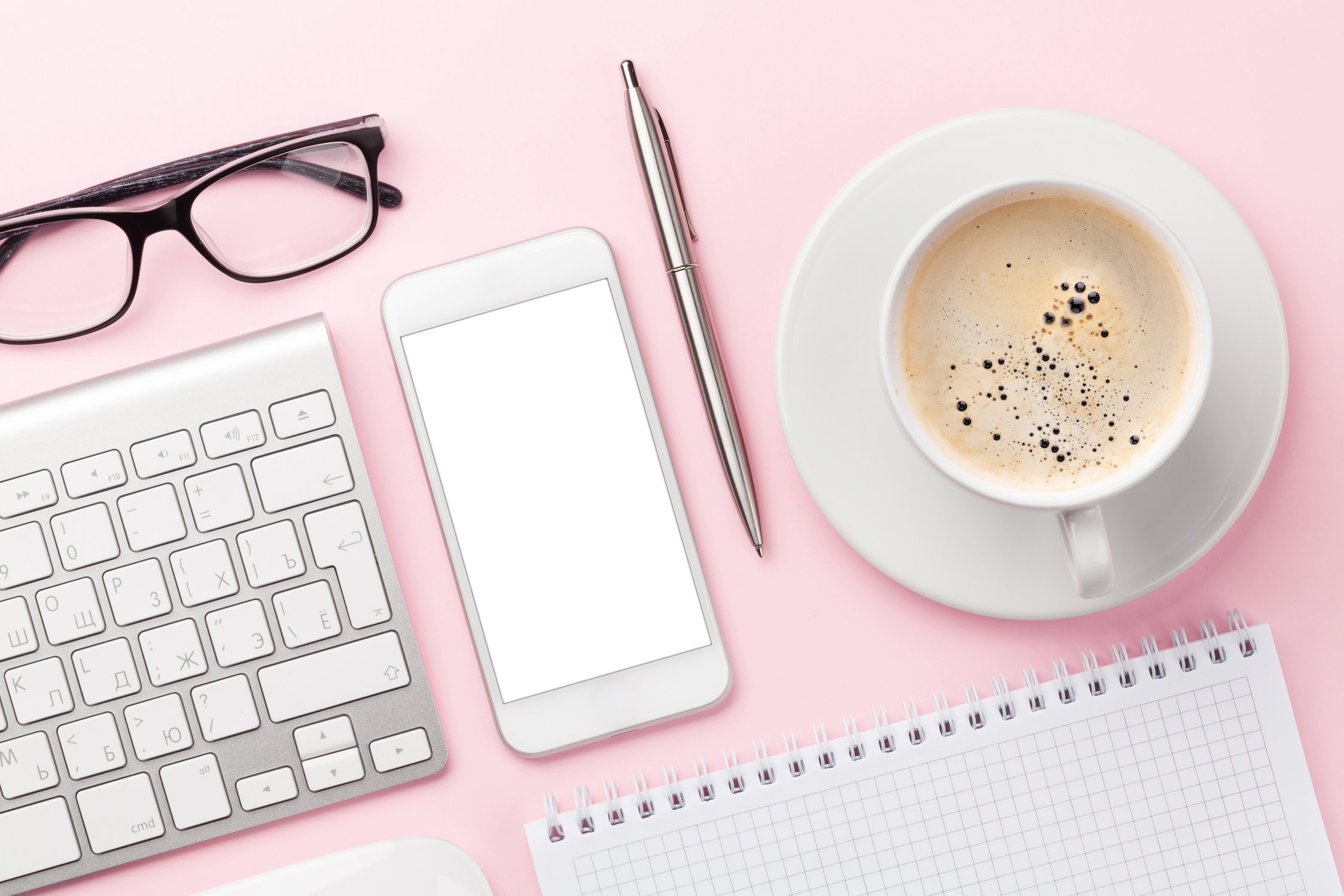 Pink workplace with computer, smartphone and coffee